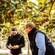 Two men holding kiwifruit in a middle of an orchard